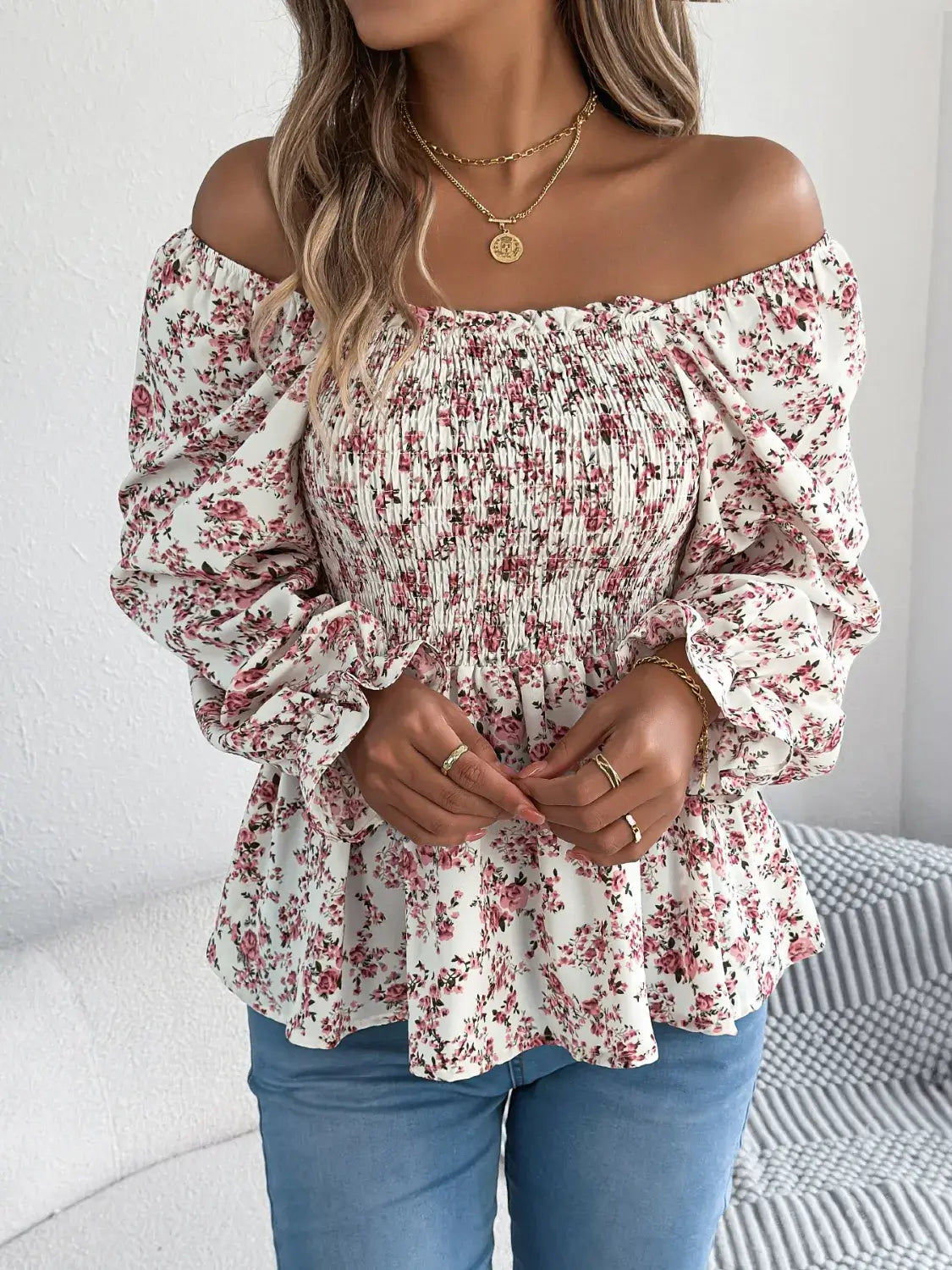 Off-shoulder floral blouse with a vibrant floral pattern, elastic neckline, and flowy sleeves, perfect for a feminine and effortless look in white standing up