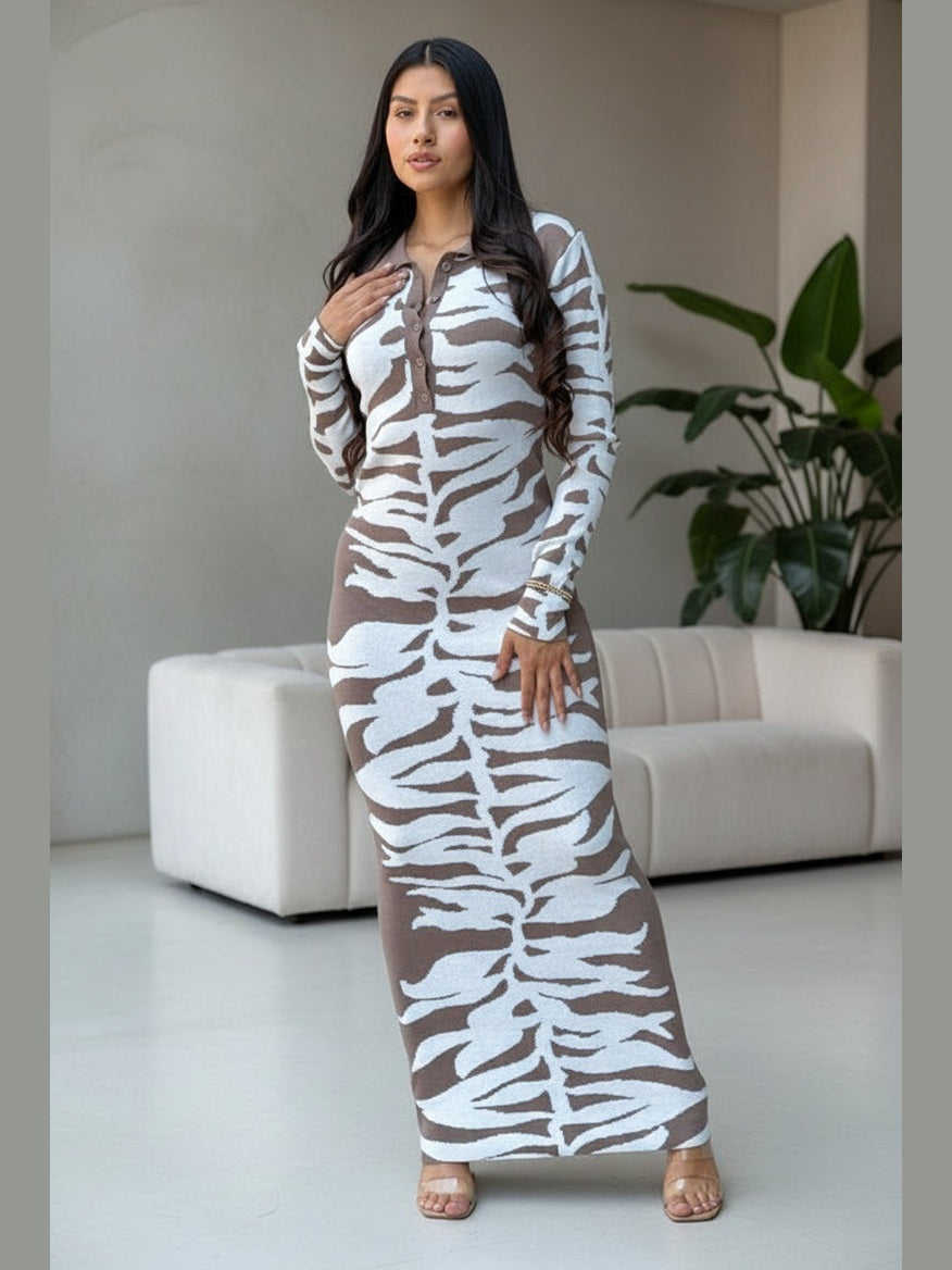 Woman wearing a long, patterned dress in a modern indoor setting.