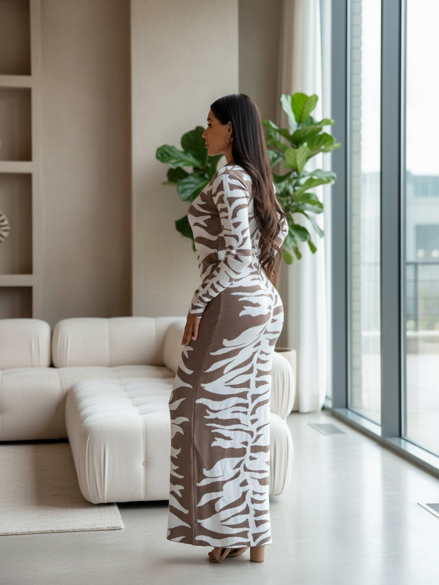 Woman in a patterned dress standing in a modern living room with a large window and white sofa.