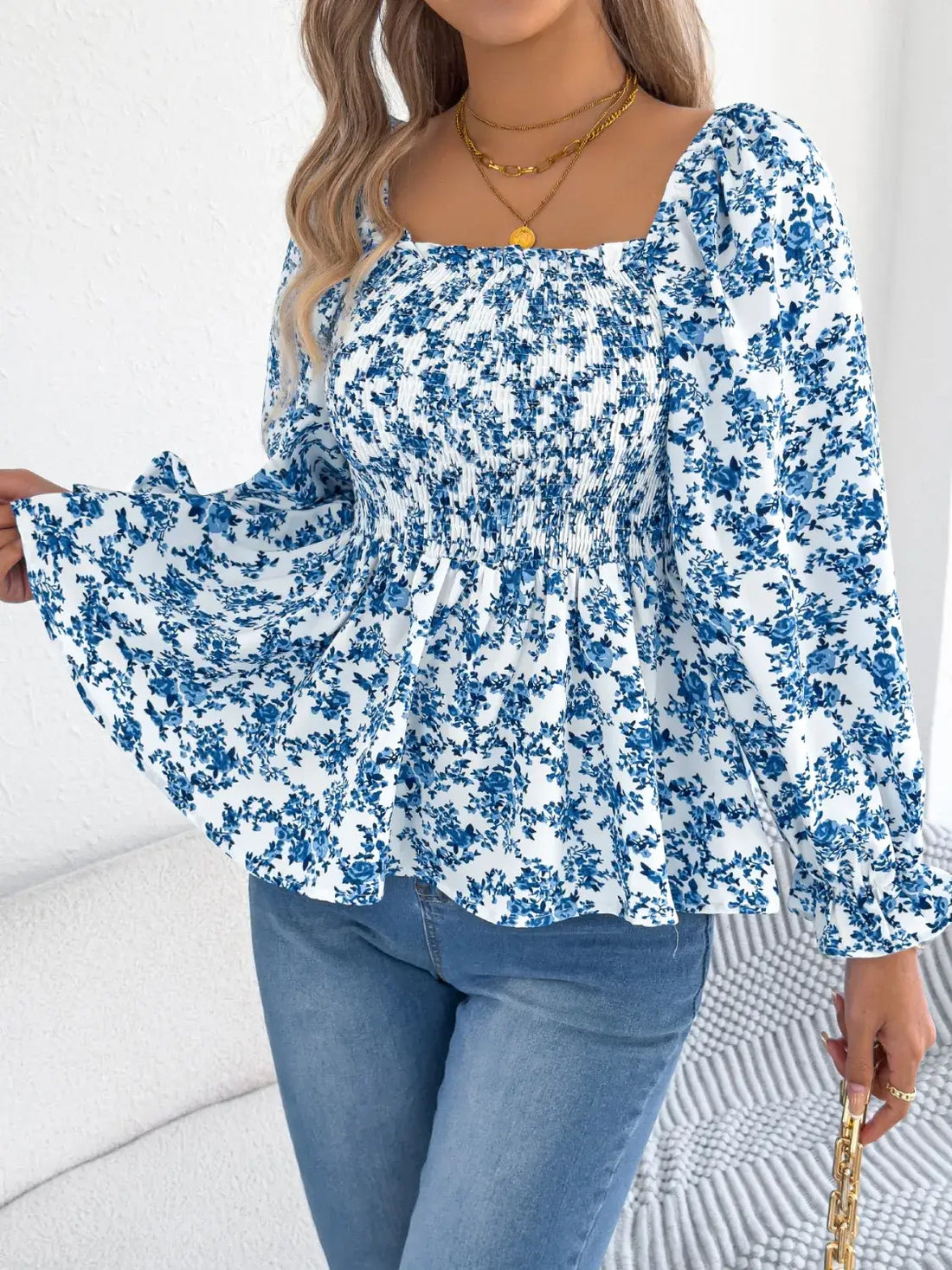 Off-shoulder floral blouse with a vibrant floral pattern, elastic neckline, and flowy sleeves, perfect for a feminine and effortless look in blue. 